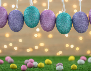 Pastel Glitter Easter Eggs Hanging In A Cute Studio Background Of Chocolate Eggs And Fairy Lights