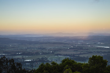 Fototapeta na wymiar View From A Lookout Above Rural Farmlands In Australia At Sunrise With Misty Blue Skies