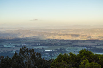 Fototapeta premium View From A Lookout Above Rural Farmlands In Australia At Sunrise With Misty Blue Skies