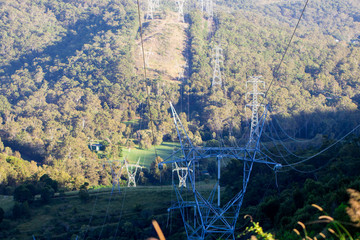 Electrical Power Lines Above Lush Green Mountain Ranges On A Sunny Day In Rural Australia