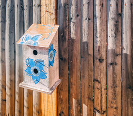 birdhouse with blue flower hanging on wood fence