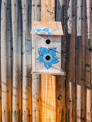 birdhouse with blue flower hanging on wood fence