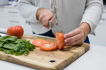 Persons Hands Cutting Up Fresh Healthy Vegetables In A Kitchen On A Timber Chopping Board