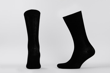 Blank black cotton high socks on invisible mannequin foot as mock up for advertising, branding, design. Back and side view, sportwear template on white background.