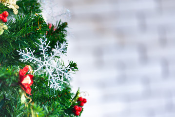 Christmas and New Year holiday concept. Closeup and blur Christmas tree decoration with ribbons balls and ornaments over white brick wall and bokeh