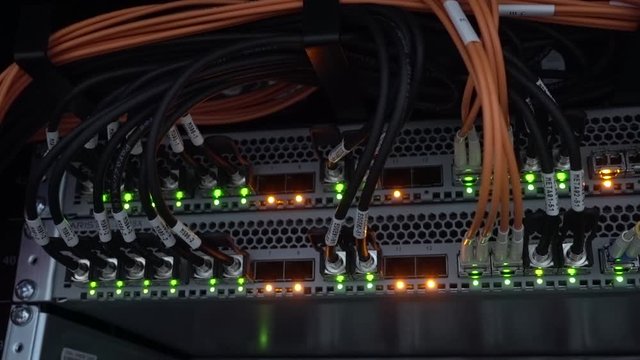 Orange and green lamps. The back of a large optical server. Camera in motion