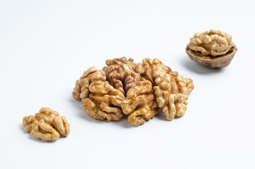 Three walnuts lying in a diagonal line, a closed walnut, half peeled walnut and half a walnut.