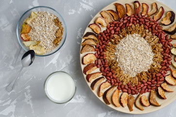 healthy breakfast of granola, nuts and dried fruits with milk, on a light gray concrete background