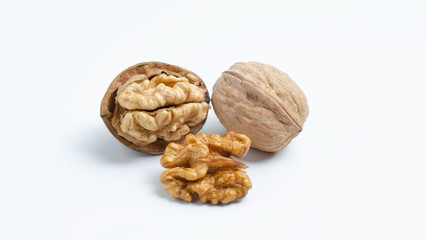 Three walnuts lying in a handful, a closed nut, half peeled walnut and half a walnut.