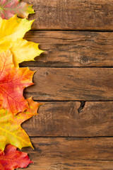 Naklejka na ściany i meble Autumn composition with frame made of colourful leaves on rustic wooden background. Top view