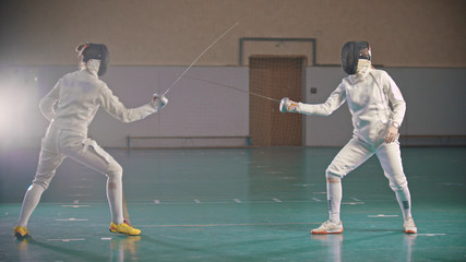 In the school gym wo fencers are training
