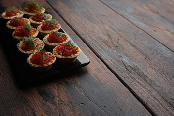 Red caviar in tartalets on a wooden table