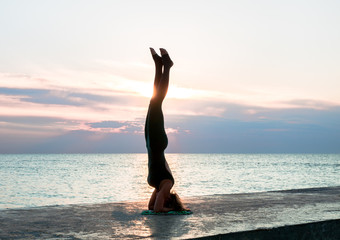 Obraz na płótnie Canvas unrecognizable senoir woman with beautiful body doing yoga splits at sunrise on the sea, silhouette of yoga poses