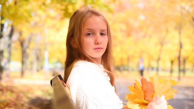 teenage girl having rest among maple trees in autumn park