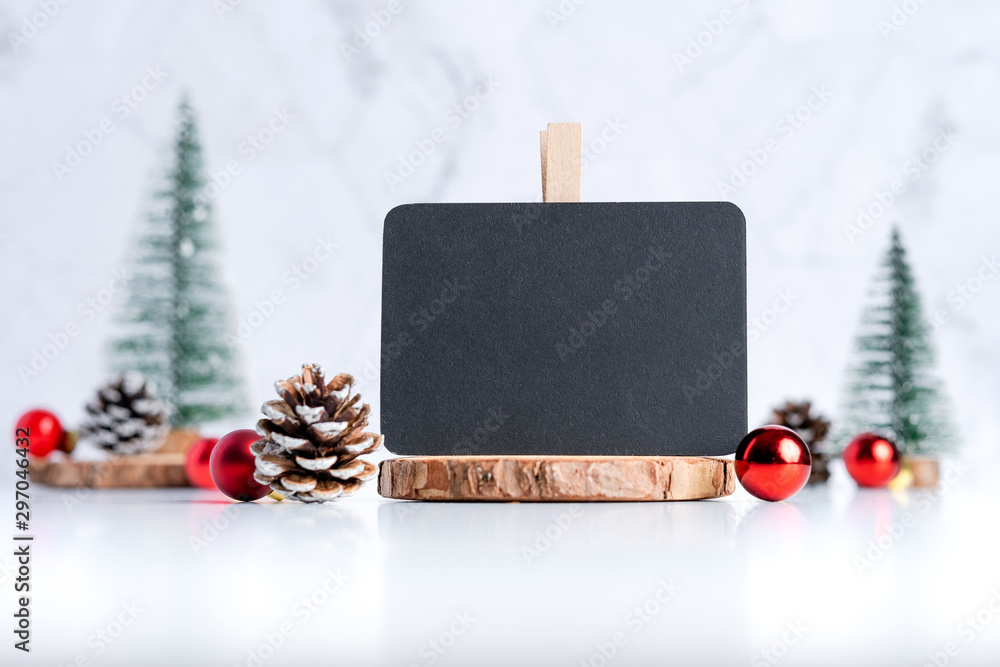 Poster blackboard with christmas tree with pine cone and decor xmas ball on white table and marble tile wall background.clean minimal simple style.holiday still life mock up banner with space to adding text
