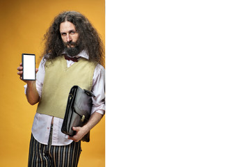 Eccentric man holding a smartphone and leaning on white board