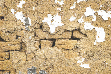 Dirty old rotten plaster on a wall texture. White paint resign and bricks visible. Vintage looking