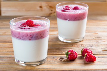 Two cups of panna cotta with a raspberry on wooden background. Selective focus