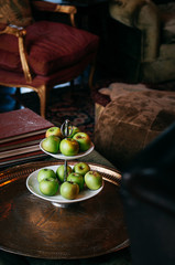 Green apple in ceramic fruit tray on antique brass table in colonial vintage living room