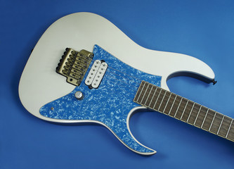 close up at the bridge of a custom electric guitar with a pickguard a gold tremolo and a white humbucker pickup
