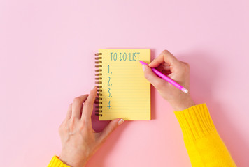 To do list in spiral notepad. Pink background, flat lay style..