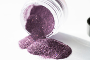Obraz na płótnie Canvas Transparent packaging jar purple sequin open on white background macro