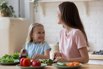 Obraz na płótnie Canvas Happy mother and adorable little daughter preparing salad together