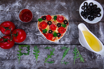 Heart shaped pizza ingredients. The name of the pizza is written in arugula.