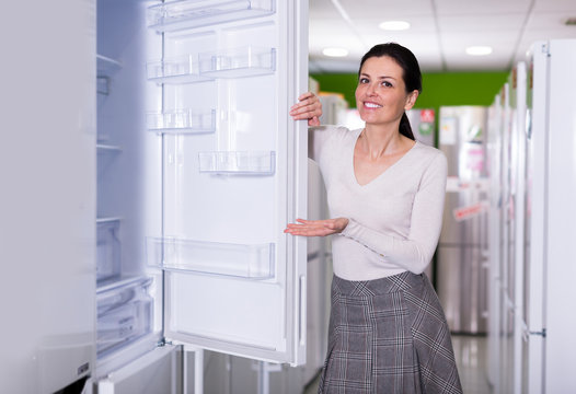 Female selecting new fridge in shop of household appliances