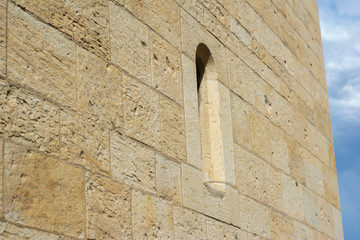 Antique wall of large stone blocks with a window against the sky. Shot in perspective at an acute angle.