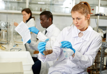 Serious woman lab  scientist in glasses working with reagents and test tubes