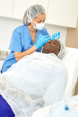 Man client and doctor during beauty facial injections in medical esthetic office