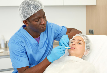 Dermatologist male preparing  woman client before  aesthetic facial procedure