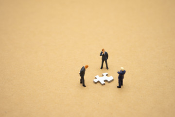 Miniature people businessmen standing on white Jigsaw. The concept used in selecting personnel to...