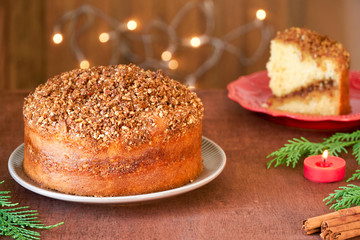 Almond cinnamon cake with christmas lights on wooden table. Close up  