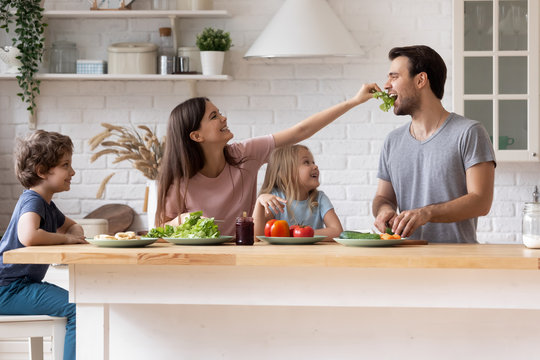 Happy Family Cooking Salad Together, Smiling Mother Feeding Father