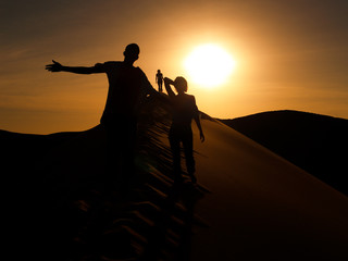 Fototapeta na wymiar A silhuette of three person walking on a dune in Namib desert