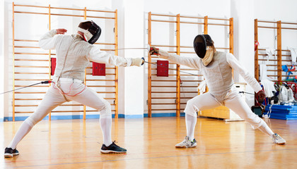 Portrait of athletes at fencing workout, practicing attack movements in duel