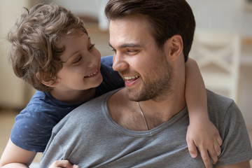 Happy father carrying little son on back, hugging, having fun