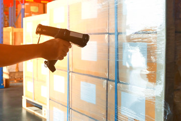 Warehouse worker holding barcode scanner scanning on goods pallet shipment to transport.