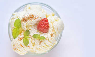 Vanilla ice cream decorated with mint leaves and ripe strawberries, sprinkled with cinnamon