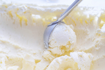 Vanilla white ice cream. Scooping ice cream ball out of container with metal spoon close up