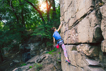 The girl climbs the granite rock.