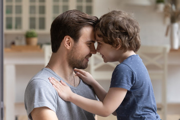 Cute little son and smiling father touching foreheads, expressing love
