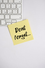 Yellow sticky note with text "Dont forget..." on the computer keyboard