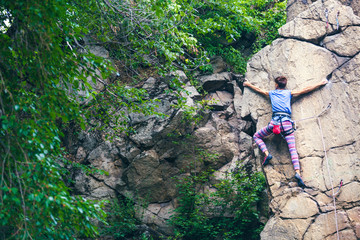 Fototapeta premium The girl climbs the granite rock.
