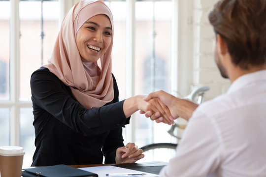 Happy asian muslim hr handshake male applicant at interview meeting