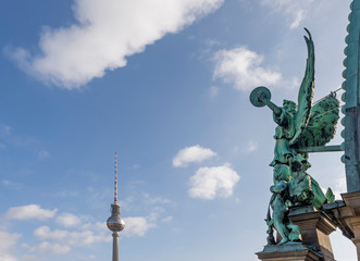 The angel of the dome of the Cathedral of Berlin, Germany and the Television Tower against a beautiful blue sky with some clouds
