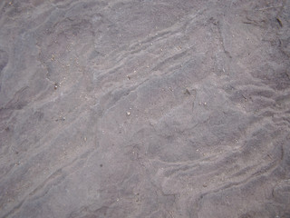 Stone with a wavy structure. Sand.