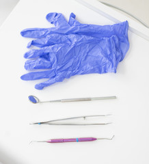 Dentist's table with sterile tools on a white background top view. A mirror, tweezers, a probe and gloves are on the doctor table. Oral hygiene, caries prevention, examination.